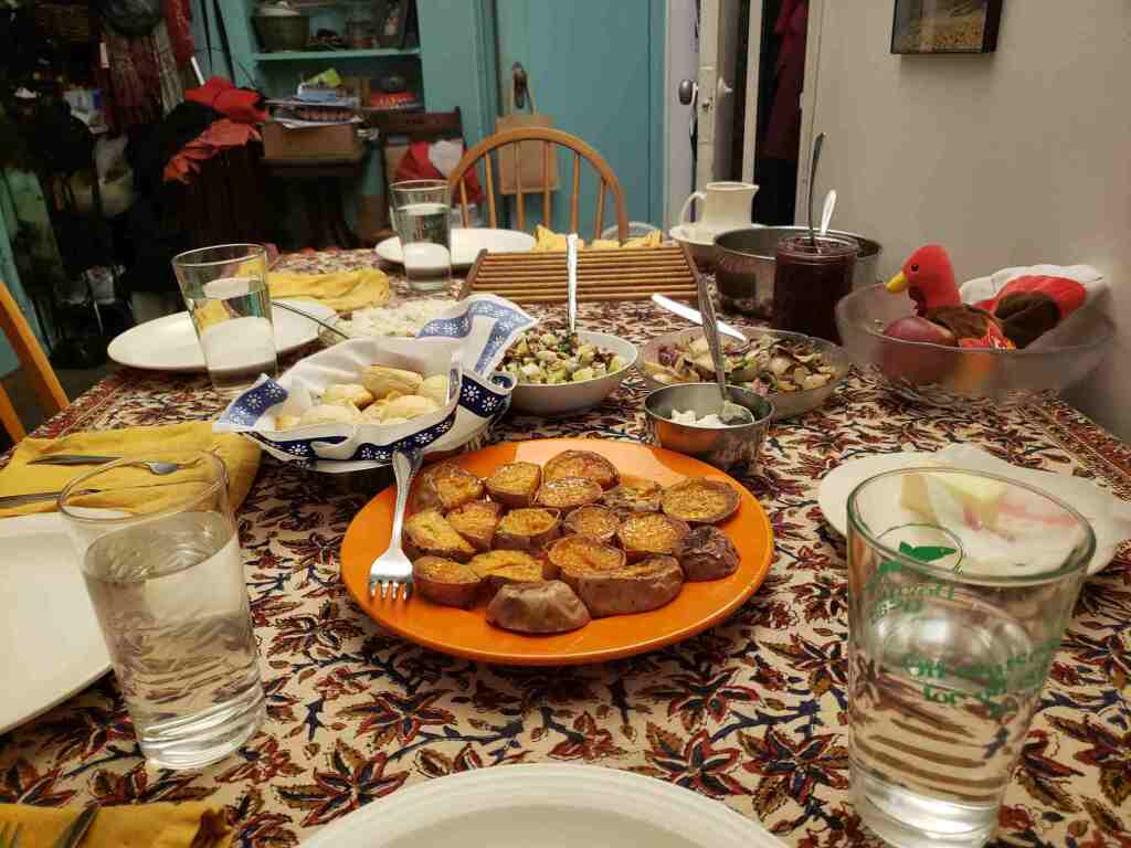 Holiday table before turkey is brought out: bowls of herbed onions, celery/pecan/shallot salad, mashed potatoes and roles. Plate of baked acorn squash medallions.
